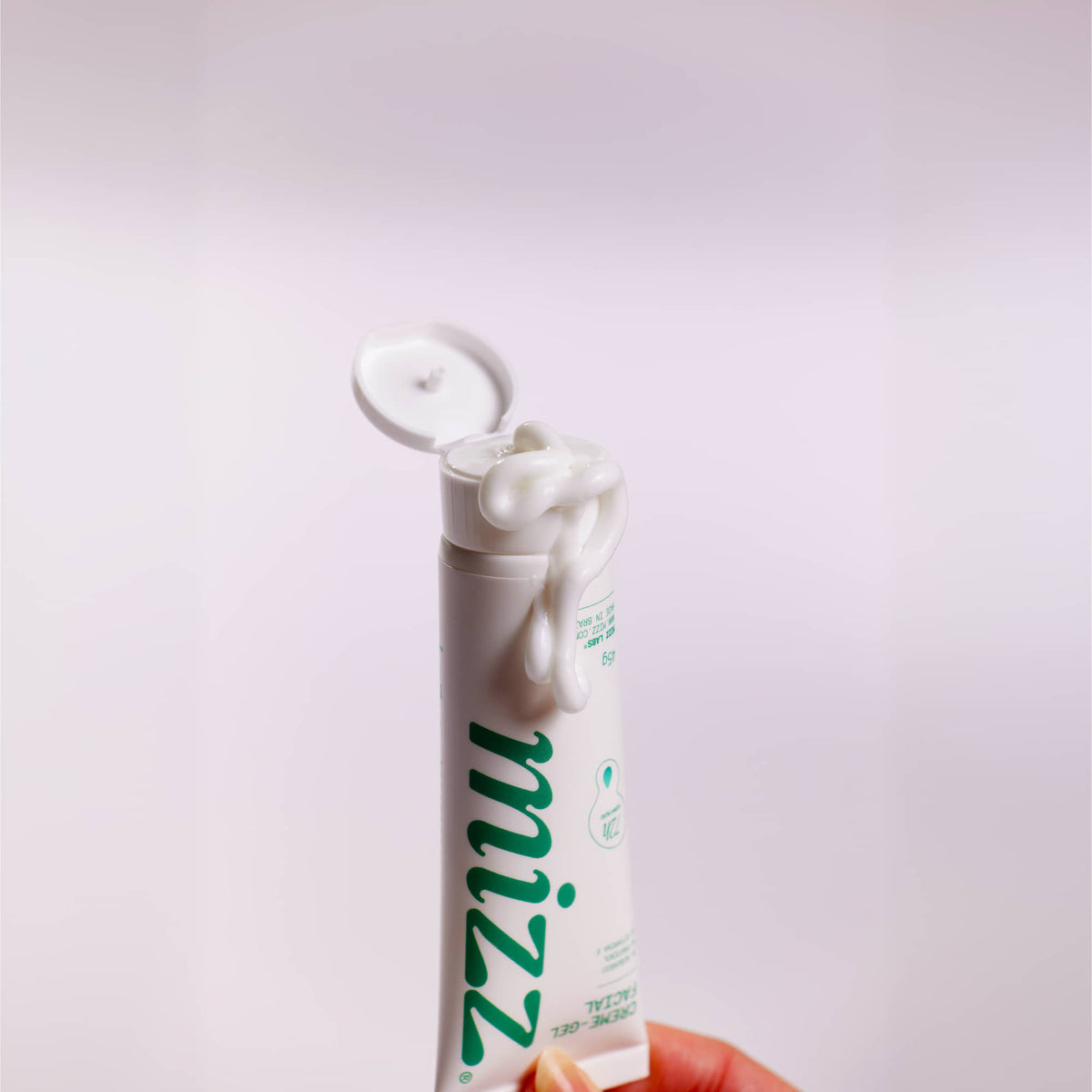 Tubo aberto do Creme Facial Hidratante 72h Mizz com creme cremoso na mão