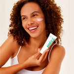 Mulher cacheada sorridente aplica Creme-gel Facial Hidratante 72h Mizz no rosto