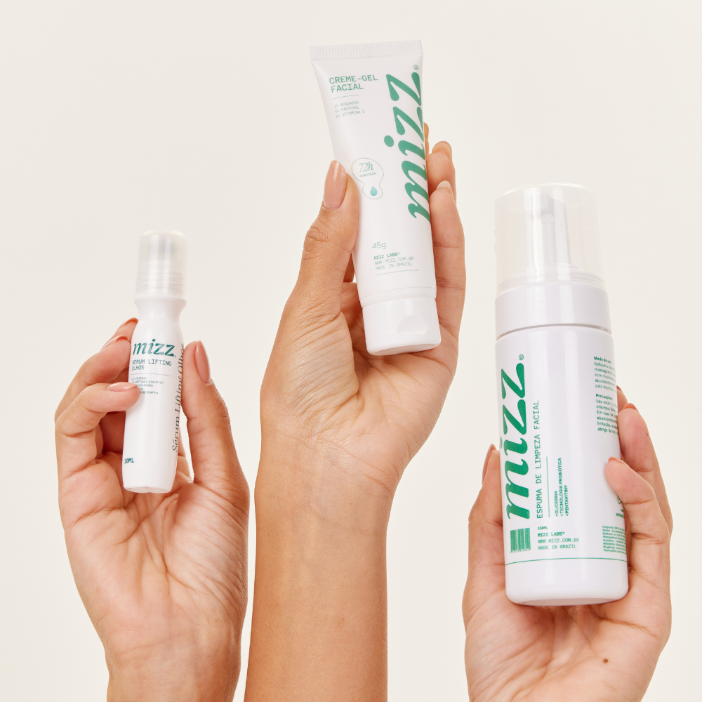 Mãos segurando o Kit Rotina Mizz: Sérum Lifting Olhos, Creme-Gel Facial 72h e Espuma de Limpeza Facial — tamanho real
